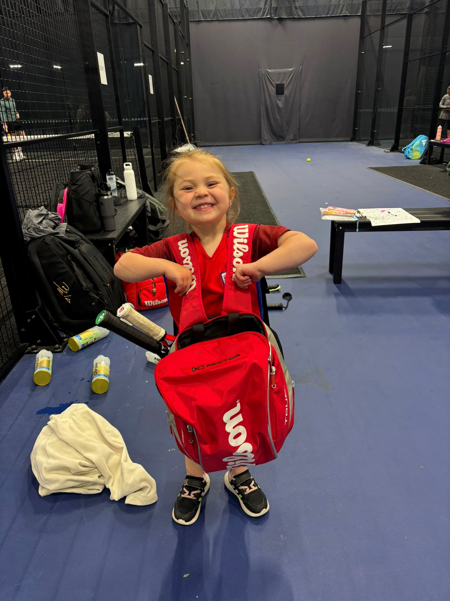A smiling young tennis player holding her equipment